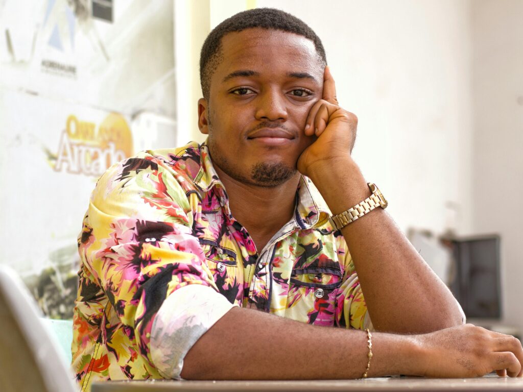 Young man wearing a colorful floral shirt, posing with a thoughtful expression indoors.