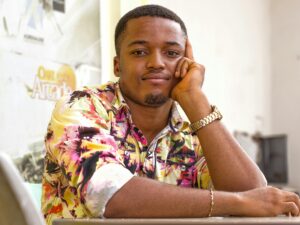 Young man wearing a colorful floral shirt, posing with a thoughtful expression indoors.