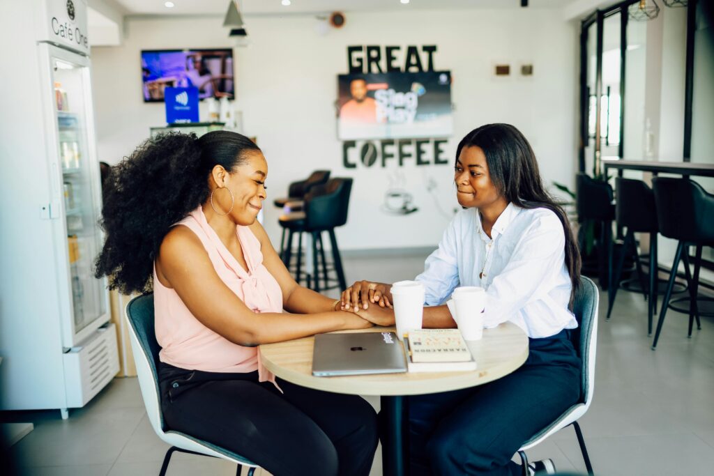 Two women sharing a joyful moment over coffee at a café in Lagos, Nigeria.